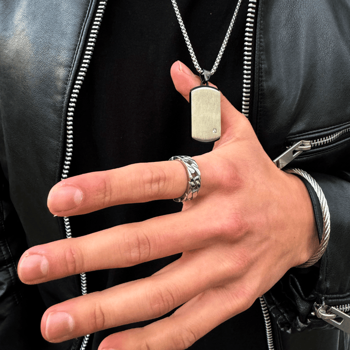 Este elegante anillo de hombre en acero inoxidable destaca por su diseño moderno y sofisticado. Con una banda ancha y un acabado pulido, es perfecto para complementar cualquier estilo. La imagen muestra el anillo en una mano masculina, resaltando su robustez y atractivo visual. Ideal para hombres que buscan un accesorio distintivo y con carácter, este anillo es tanto una declaración de estilo como una pieza versátil para el uso diario.